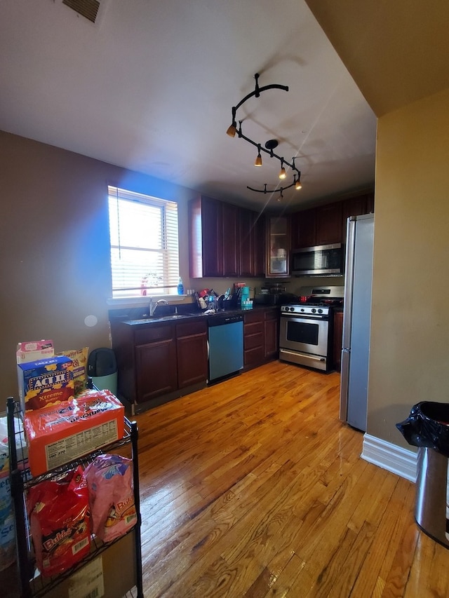 kitchen with appliances with stainless steel finishes, track lighting, light hardwood / wood-style floors, sink, and dark brown cabinets