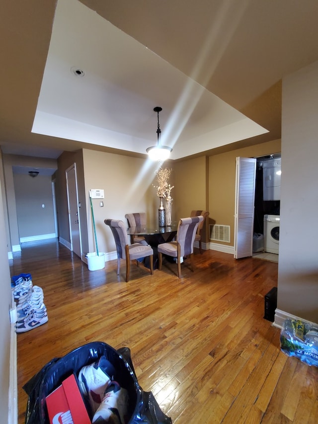 living room featuring washer / dryer, a tray ceiling, and hardwood / wood-style flooring