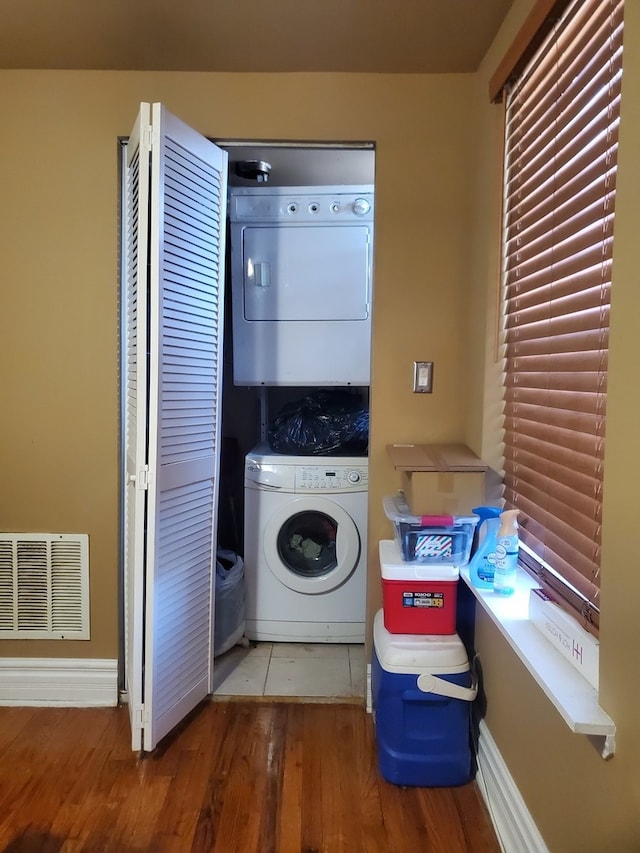 clothes washing area with dark hardwood / wood-style flooring and stacked washer / drying machine