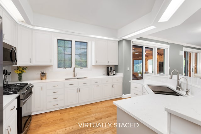 kitchen featuring range with gas cooktop, light hardwood / wood-style floors, white cabinets, and sink