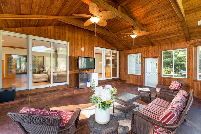 living room with beamed ceiling, wooden ceiling, ceiling fan, and wooden walls