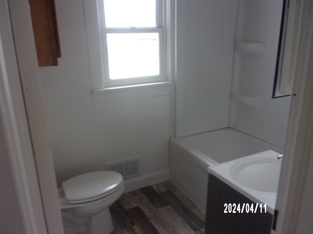 full bathroom featuring hardwood / wood-style floors, vanity, toilet, and shower / tub combination