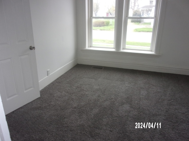 unfurnished room with dark colored carpet