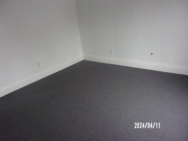 spare room featuring dark colored carpet