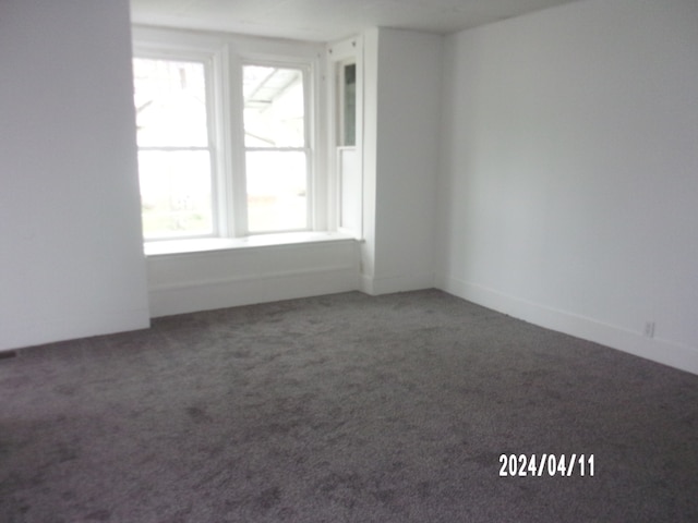 spare room with plenty of natural light and dark carpet