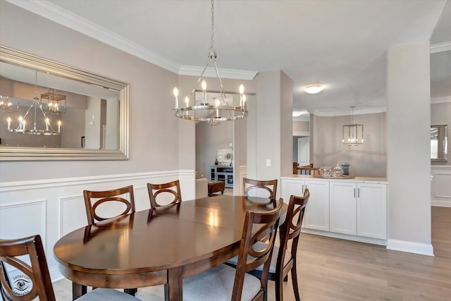 dining area with a notable chandelier, light hardwood / wood-style floors, and crown molding