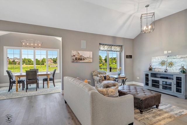 living room featuring vaulted ceiling, light wood-type flooring, and a chandelier