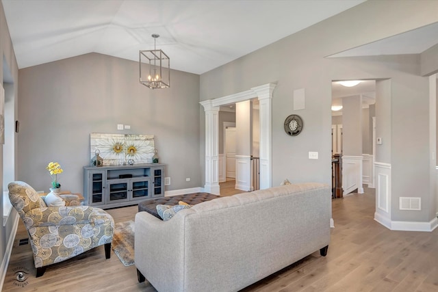 living room featuring vaulted ceiling, decorative columns, and light wood-type flooring