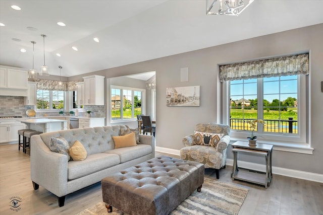 living room featuring light hardwood / wood-style flooring, high vaulted ceiling, and a notable chandelier