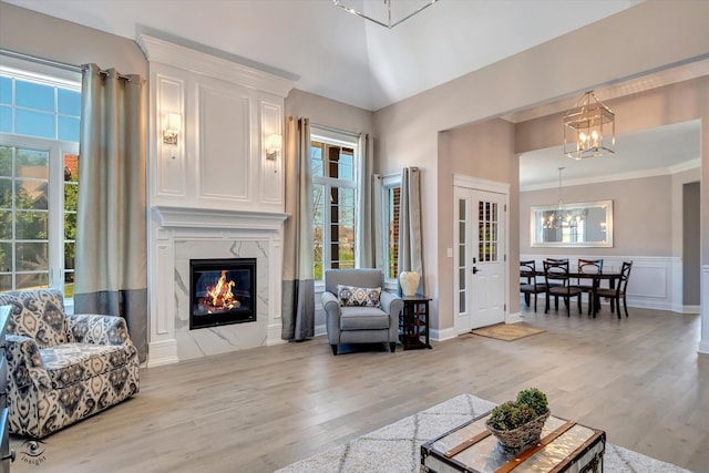 living room with a chandelier, a high end fireplace, and light hardwood / wood-style floors