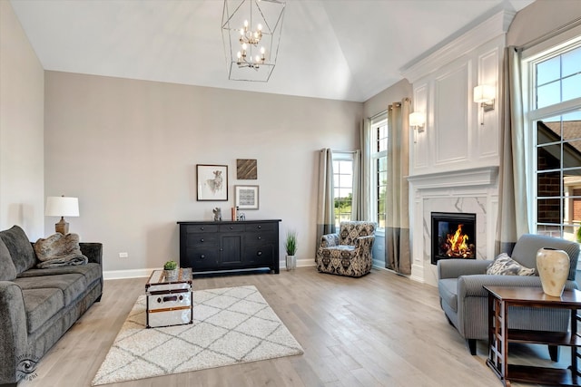 living room featuring a high end fireplace, light hardwood / wood-style flooring, and a notable chandelier