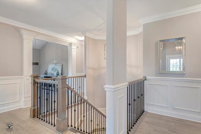 corridor featuring crown molding, light hardwood / wood-style flooring, and decorative columns