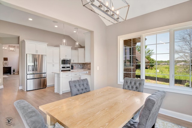 dining space with plenty of natural light, light hardwood / wood-style floors, a notable chandelier, and lofted ceiling