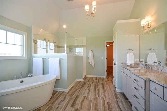 bathroom with vanity, separate shower and tub, and an inviting chandelier