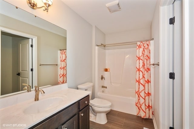 full bathroom with toilet, vanity, and shower / tub combo with curtain