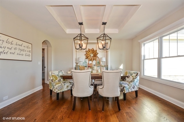 dining room featuring dark hardwood / wood-style floors, a raised ceiling, and a notable chandelier