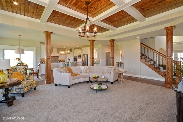 living room featuring a notable chandelier, ornate columns, and coffered ceiling