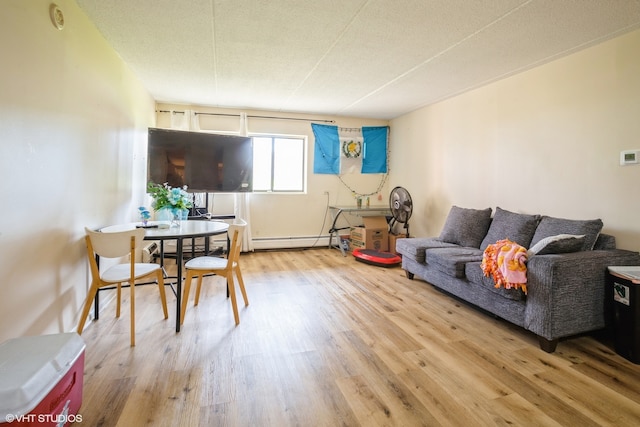 living room with baseboard heating, light hardwood / wood-style flooring, and a textured ceiling