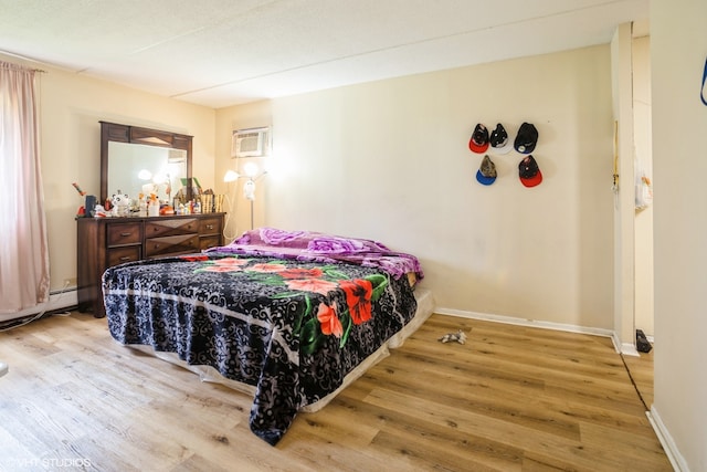 bedroom with a wall unit AC, hardwood / wood-style flooring, and baseboard heating