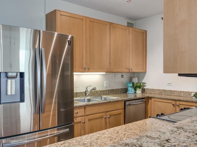 kitchen featuring appliances with stainless steel finishes, sink, backsplash, and light stone counters