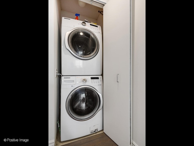 washroom with dark hardwood / wood-style floors and stacked washer and dryer