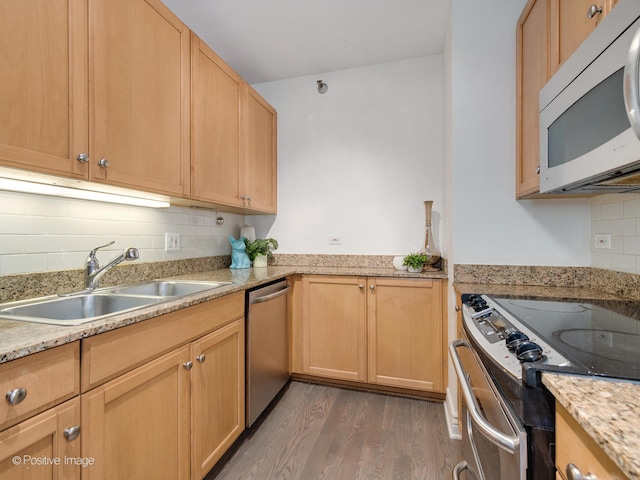 kitchen with light stone counters, appliances with stainless steel finishes, sink, tasteful backsplash, and dark wood-type flooring