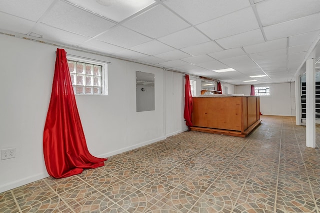 basement with plenty of natural light, tile floors, and a drop ceiling