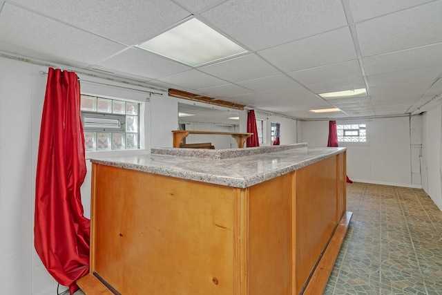 kitchen featuring a paneled ceiling, tile floors, and light stone countertops