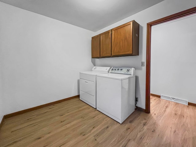 clothes washing area featuring light hardwood / wood-style floors, cabinets, and separate washer and dryer