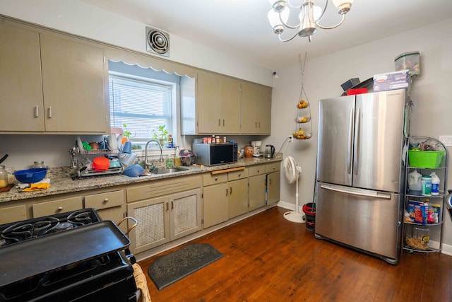 kitchen featuring appliances with stainless steel finishes, light stone counters, sink, dark hardwood / wood-style flooring, and a chandelier