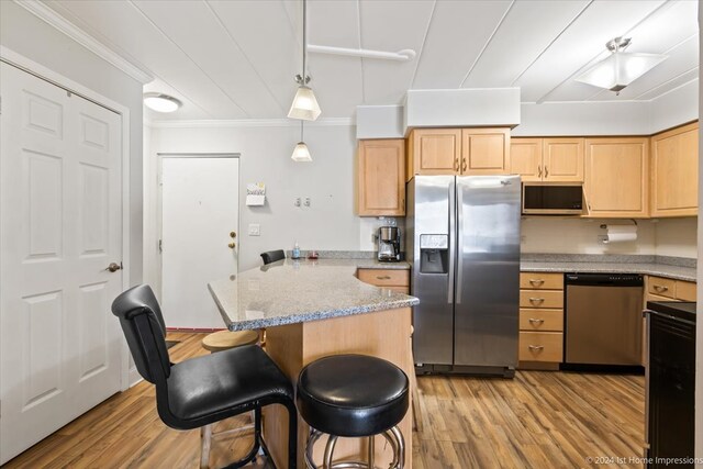 kitchen with light hardwood / wood-style floors, appliances with stainless steel finishes, hanging light fixtures, and light stone counters