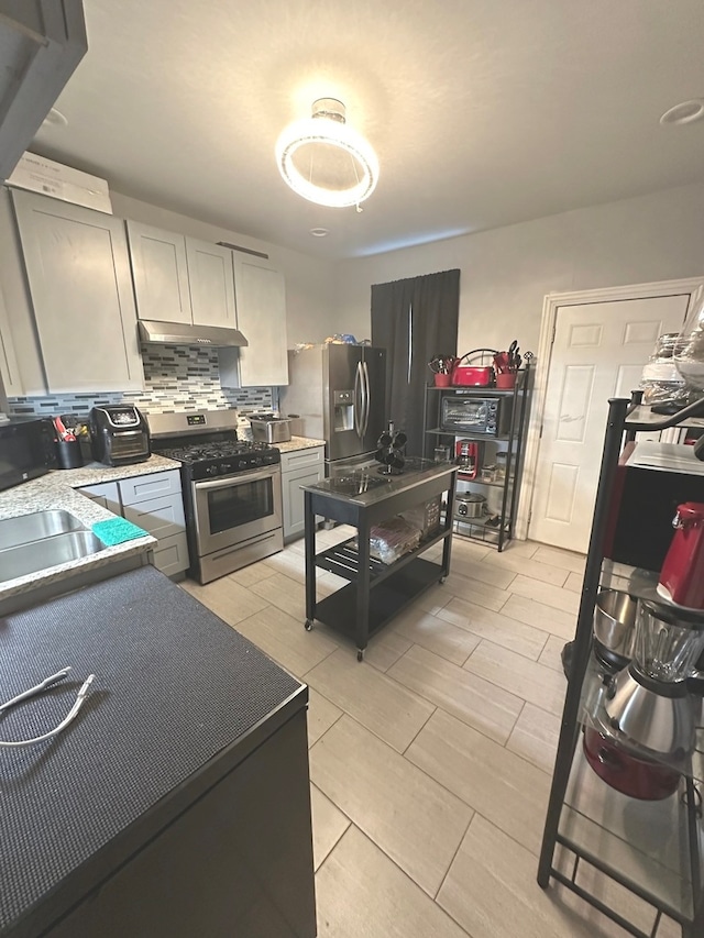 kitchen featuring appliances with stainless steel finishes, decorative backsplash, and gray cabinetry