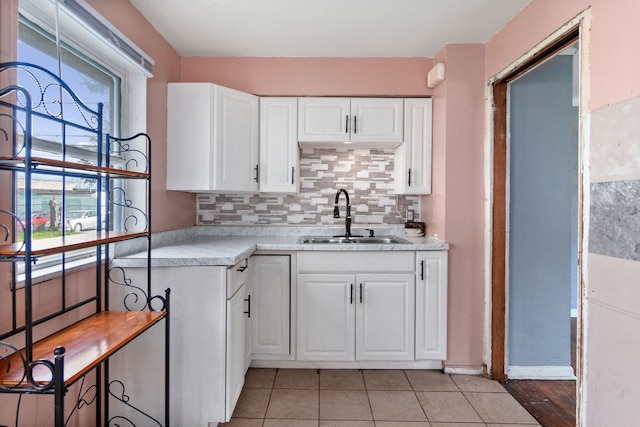 kitchen with light tile floors, white cabinetry, and sink