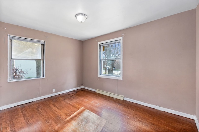 unfurnished room featuring wood-type flooring, plenty of natural light, and baseboard heating