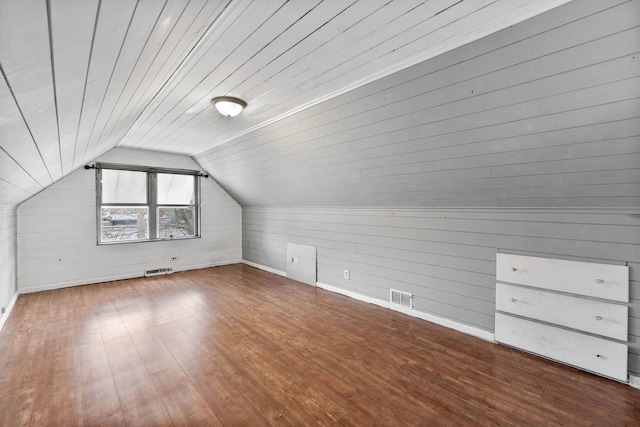 additional living space with wood ceiling, vaulted ceiling, wood walls, and dark wood-type flooring