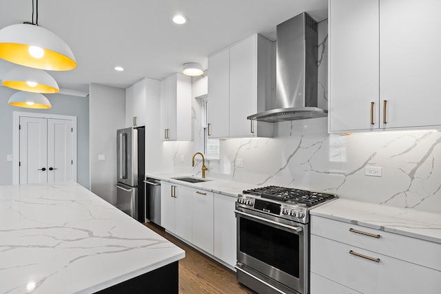 kitchen with appliances with stainless steel finishes, backsplash, hanging light fixtures, wall chimney range hood, and sink