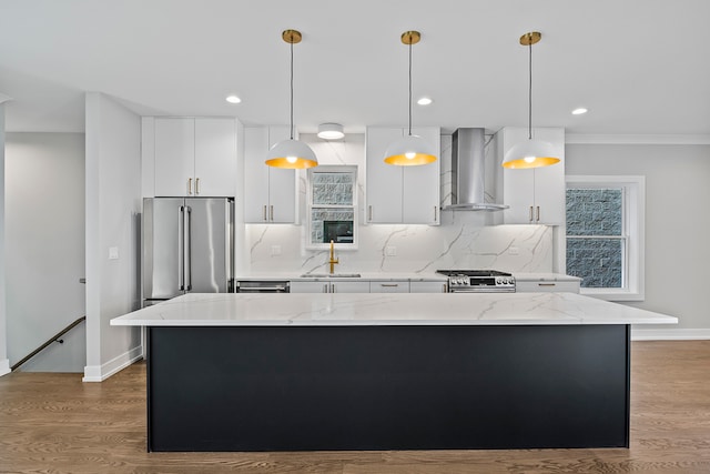 kitchen featuring a center island, hanging light fixtures, light hardwood / wood-style flooring, wall chimney range hood, and stainless steel appliances