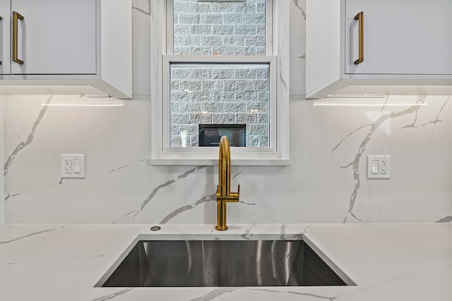 kitchen with white cabinets, sink, a fireplace, and light stone countertops