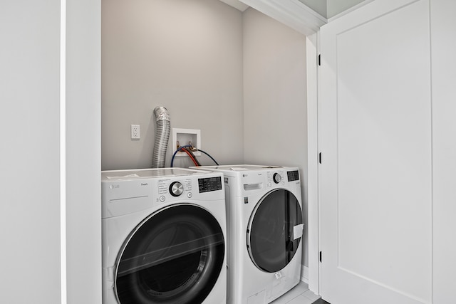 clothes washing area featuring washing machine and dryer, light tile floors, and washer hookup