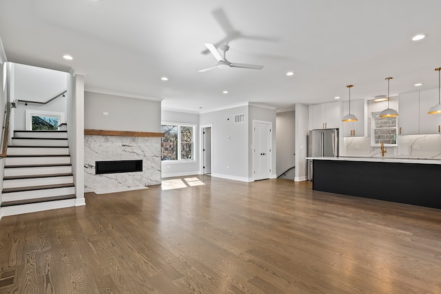 living room featuring dark hardwood / wood-style flooring, ceiling fan, crown molding, and a premium fireplace