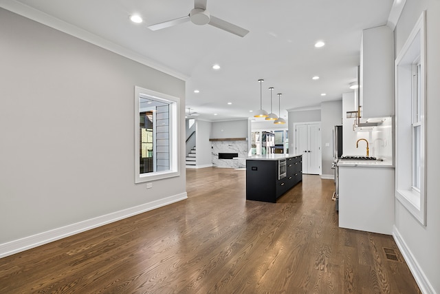 kitchen featuring decorative light fixtures, dark hardwood / wood-style flooring, backsplash, a center island with sink, and ceiling fan