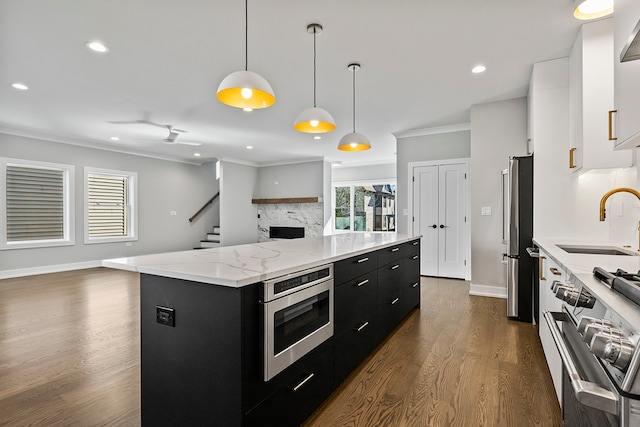 kitchen featuring pendant lighting, dark hardwood / wood-style flooring, ornamental molding, stainless steel appliances, and sink