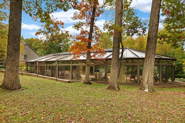 rear view of house featuring a sunroom and a lawn