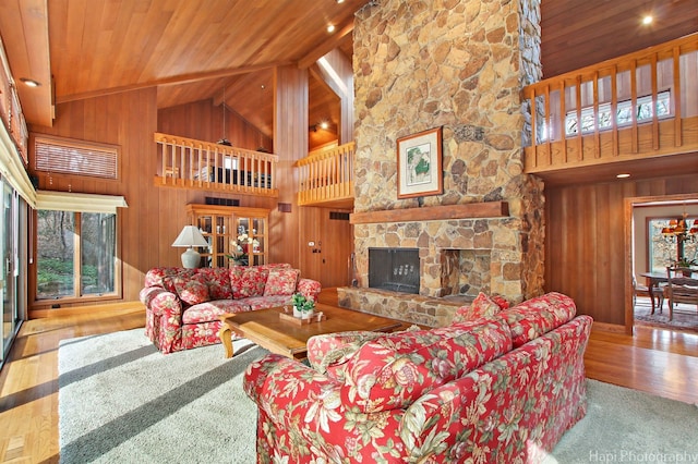 living room with wood ceiling, wood walls, high vaulted ceiling, and a stone fireplace