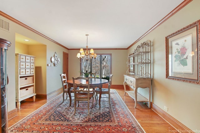 dining space with a notable chandelier, crown molding, and light wood-type flooring