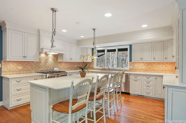 kitchen with a kitchen island, a kitchen breakfast bar, decorative light fixtures, and stainless steel dishwasher