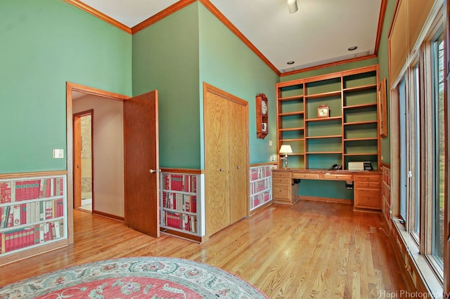 unfurnished office with ornamental molding, built in desk, and light wood-type flooring