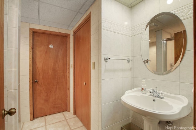 bathroom with tile walls, a drop ceiling, sink, and tile floors