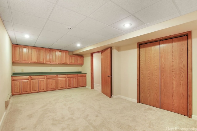 interior space featuring light carpet and a paneled ceiling