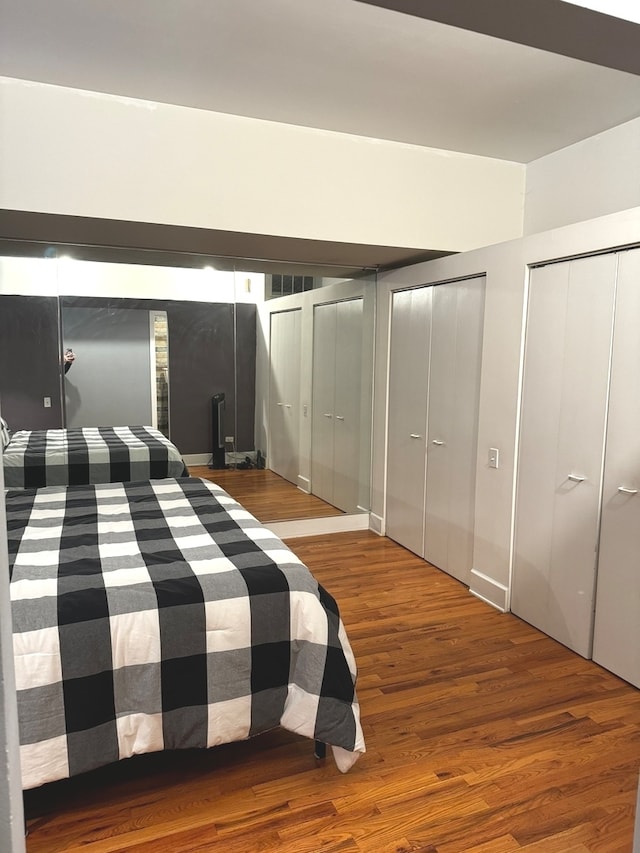 unfurnished bedroom featuring hardwood / wood-style floors and two closets